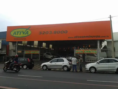 Fachada com grande painel laranja da Ativa Seminovos sobre a loja de veículos