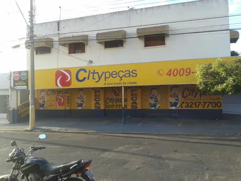 Fachada amarela da Citypeças com logo vermelho e adesivos de personagens no tapume inferior