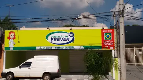Fachada amarela da Farmácia Prever com logo verde, personagem e selo Farmácia Popular