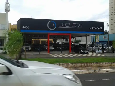 Fachada escura com logo Jackson e estrutura vermelha de pórtico em revenda de veículos