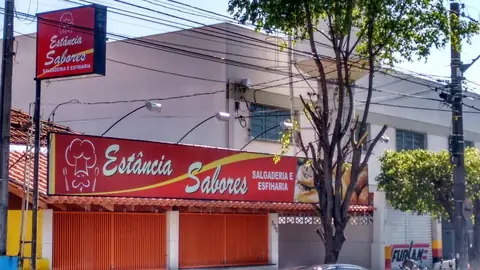 Fachada vermelha da Estância Sabores salgaderia com letreiro em caixa e placa em poste