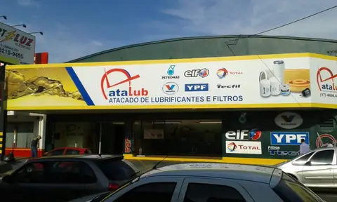 Fachada amarela e branca da Atalub, atacado de lubrificantes, com logos de marcas parceiras