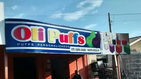 Letreiro azul com letras vermelhas e amarelas da Oli Puffs e imagem de puffs coloridos