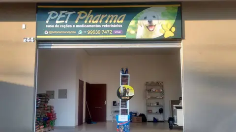 Placa iluminada verde da Pet Pharma com cachorro, sobre loja de rações