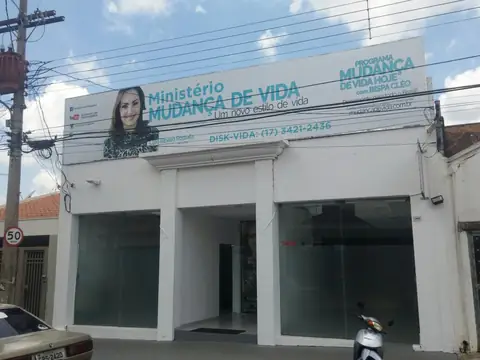 Fachada branca com painel Ministério Mudança de Vida, retrato de mulher e telefone