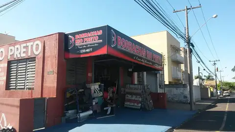 Fachada de esquina vermelha e azul da Borrachas Rio Preto com letreiros em quina