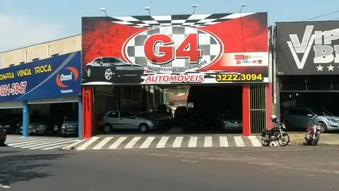 Fachada da G4 Automóveis com grande painel vermelho de bandeira quadriculada