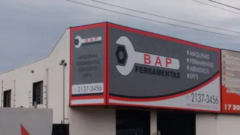 Fachada de esquina da BAP Ferramentas com painéis cinza e vermelho e chave inglesa