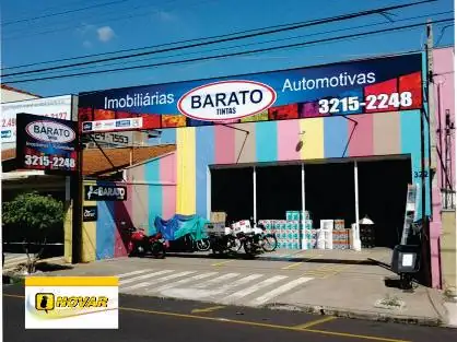 Fachada colorida de listras pastel com faixa azul da Barato Tintas e telefone em destaque