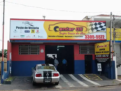 Fachada vermelha e azul da Center Oil troca de óleo com painel amarelo e bandeira quadriculada