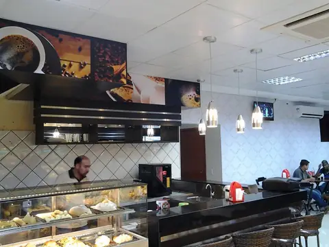 Cafeteria com painéis impressos de café e pães acima do balcão e vitrines