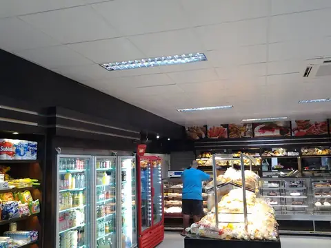 Padaria e mercearia com faixa de painéis impressos de alimentos no alto e geladeiras vermelhas