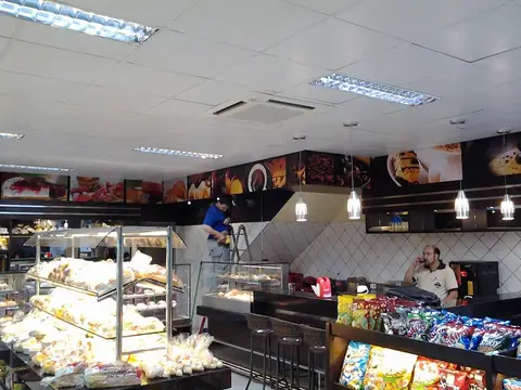 Padaria com painéis impressos de comida acima do balcão e luminárias pendentes