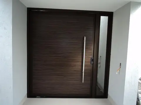 Porta pivotante em madeira escura com puxador longo de inox e lateral fixa de vidro